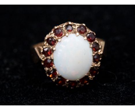 An opal and garnet cluster 9ct gold ring, set with a large oval opal approx 9mm x 11mm, with a garnet set surround, size P, w