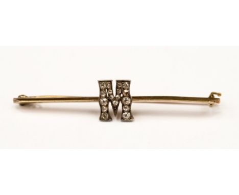 An Edwardian yellow metal bar brooch with a diamond set ' M '  with small old cut diamonds. The brooch measuring approx 50mm 