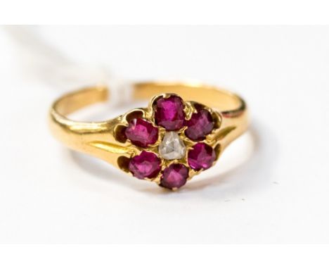 An ruby and diamond 18ct gold ring, set with an old cut diamond to the centre with a surround of six rubies, size K, total gr