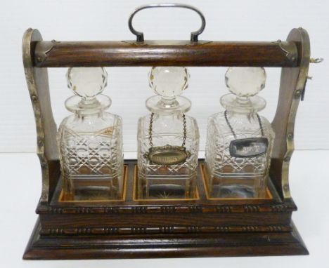 Oak and silver plated three-bottle tantalus containing three matching cut glass decanters and stoppers, with two silver plate