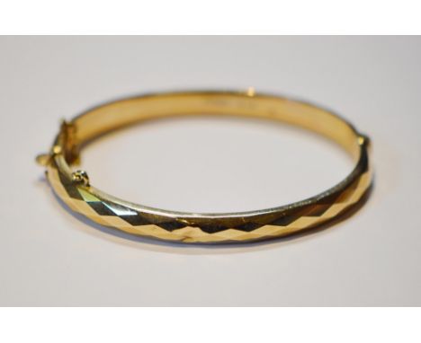 9ct gold lady's bangle, stamped '375', with attached safety chain, 6.5cm diameter, 10.3g gross.