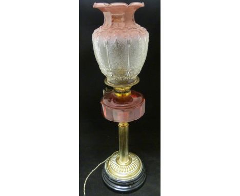 Duplex oil lamp, c. early 20th century, with cranberry glass reservoir, above brass fluted cylindrical column and base, on eb