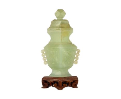 A Chinese carved jade vase and cover Attached to a wooden stand, total height 19cm, width 9cm, depth of stand 5cm.