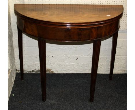 A late George III mahogany card table, the demi lune foldover top raised on fluted tapered legs, top cracked, W91cm