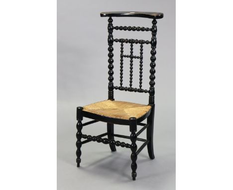 A French ebonised wooden chapel chair with a woven rush seat, &amp; on bobbin-turned supports.