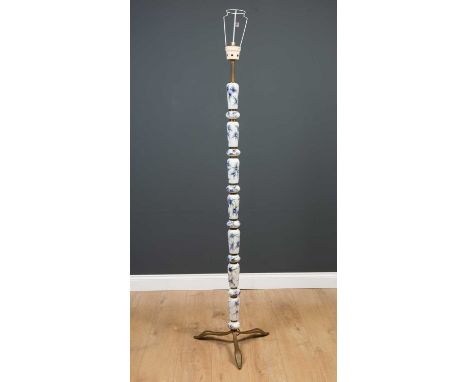 A brass framed ceramic standard lamp the sectional ceramic pieces decorated with blue and gilt highlighted flowers, on brass 