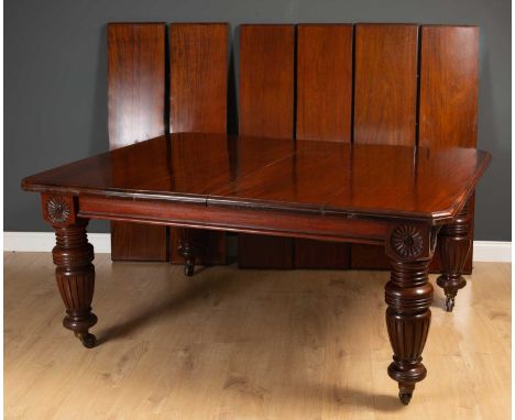 A large Victorian mahogany extending dining table with carved sunflower corners, turned legs and brass and ceramic casters, 1