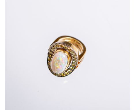 Damenring 750 GG (1960/70er Jahre), besetzt mit: 1 Opal-Cabochon, L. ca. 1,6 cm u. 24 kl.gelben Schmucksteinen im Brillantsch