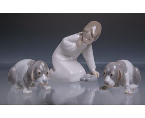 3-teilige Porzellanfigurengruppe "Mädchen mit Hunden" (wohl 20. Jh.), polychrom bemalt,bestehend aus: 1x knieendes Mädchen im