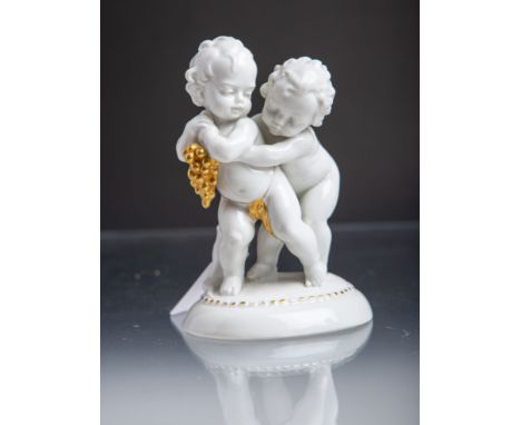 Keramikfigurengruppe "Putten m. Trauben" (Katzhütte), weiß m. Goldstaffage, blaueUnterbodenmarke, H. ca. 14 cm. Gold berieben