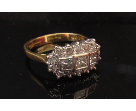 An 18ct gold diamond cluster ring three radiant cut diamonds framed by 14 round cut diamonds. Size M/N, 5.1g