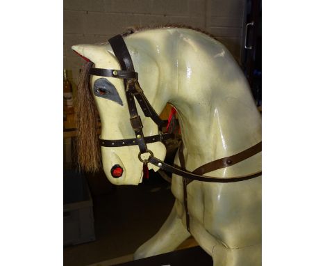 A large painted rocking horse on trestle base, with removeable leather bridle, tacked on saddle, 116cm high, 152cm long.