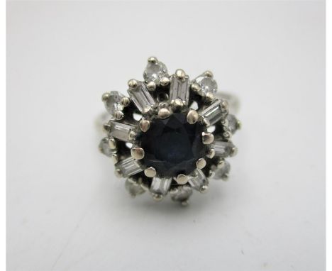 A sapphire and diamond snowflake cluster ring, in an unmarked white metal setting, with central sapphire flanked with baguett