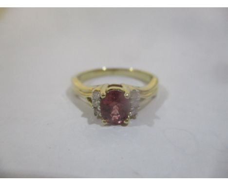 A gold coloured ring set with an oval cut red sapphire approximately 0.8ct flanked by six diamonds, stamped 10k, with a certi