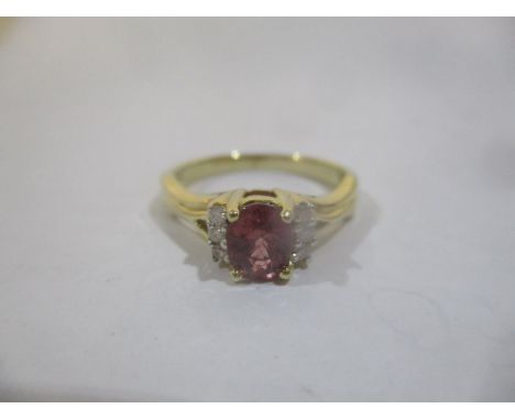 A gold coloured ring set with an oval cut red sapphire approximately 0.8ct flanked by six diamonds, stamped 10k, with a certi