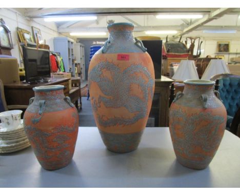 An Asian pottery vase decorated with a Phoenix in flight, along with a pair of smaller matching vases 