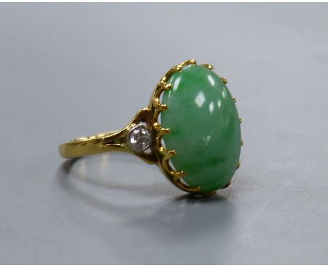   A jade and diamond dress ring, 18ct yellow gold setting,the oval cabochon jade flanked by two small diamonds, size O, gross