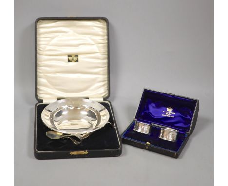   A cased christening dish with associated pusher and spoon, together with a cased pair of silver napkin rings.