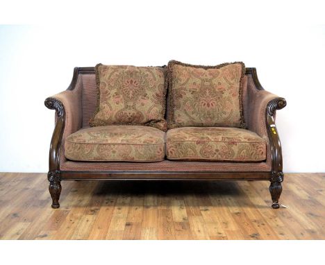A William IV style two seater sofa, the carved foliate top rail, over high scrolled sides, raised on acanthus leaf supports, 