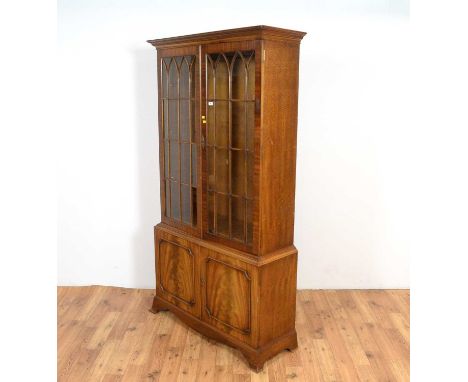A Georgian style mahogany and fiddle back mahogany bookcase, the flared top over lancet style astraglazed doors, the lower se
