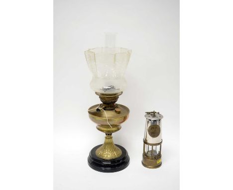 An early 20th Century brass oil lamp, with brass reservoir, floral decorated frilled glass shade and clear funnel, raised on 