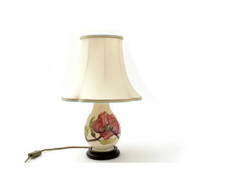 A Moorcroft magnolia pattern lamp of pear shape, fitted wood base and cream fabric shade, the ceramic 19cms.