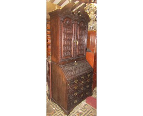 A Georgian walnut bureau cabinet with later Victorian carved foliate detail, the cabinet with broken architectural pediment o