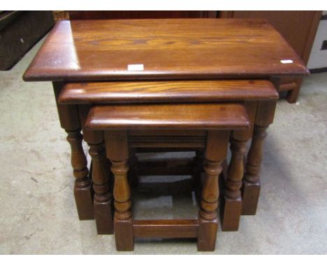 A nest of three good quality reproduction Old English style oak occasional tables, raised on turned block supports, united by