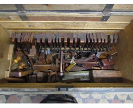 A 19th century stained pine carpenters tool chest with hinged lid enclosing removable segmented trays containing a comprehens