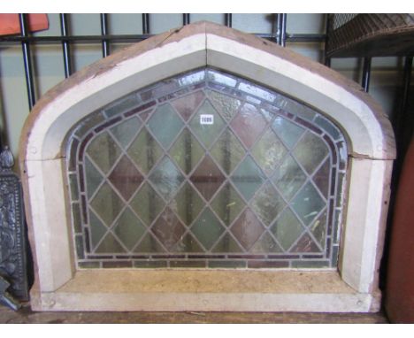 A reclaimed painted pine framed casement window of Gothic arched form enclosing a coloured leaded light panel, 87 cm long x 6