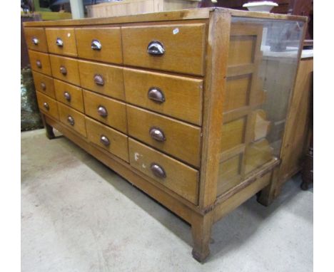 A vintage medium to light oak haberdashery cabinet/counter, with glazed panels and fitted with an arrangement of drawers with