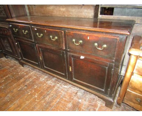 An 18th century oak dresser, this practical piece enclosed by three panel doors and three frieze drawers, raised on bracket s
