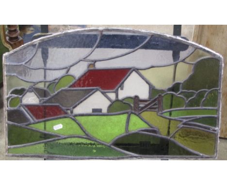 A reclaimed leaded light, possibly 1920/30s, panel of rectangular arched form with red roofed cottage in a pastoral landscape
