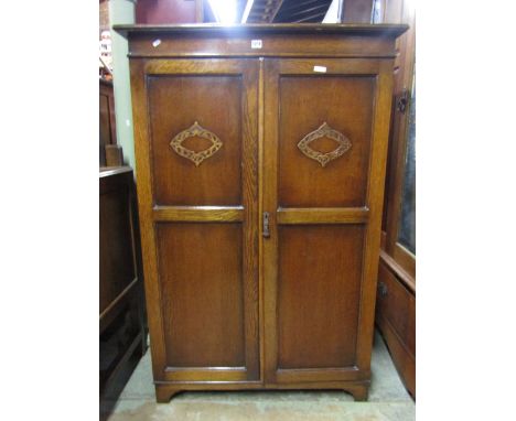 A dwarf oak gentlemen's wardrobe, the top with shallow hinged segmented compartment with mirror panel over a pair of full len
