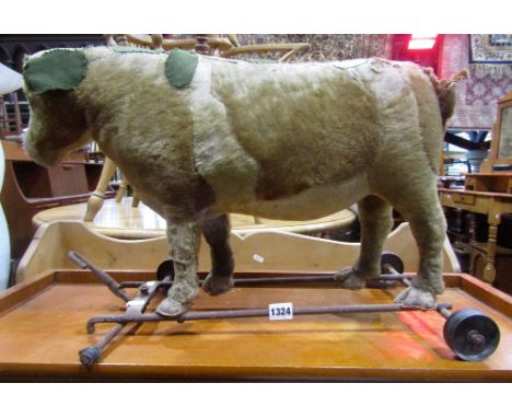 An old child's straw filled pull along toy bull/cow raised on an iron framework (possibly Steiff) (AF)