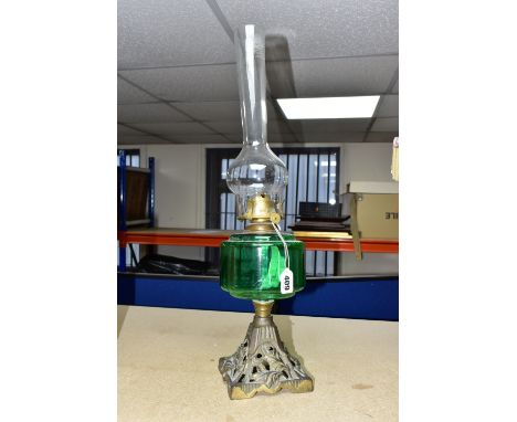 A VICTORIAN OIL LAMP, with a green glass reservoir, cast foliate base and a Diamond Brand clear glass chimney (1) (Condition 