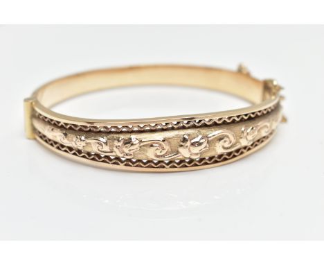 A MID 20TH CENTURY SMITH AND PEPPER 9CT YELLOW GOLD HINGED BANGLE, the front designed as an embossed foliate design with open