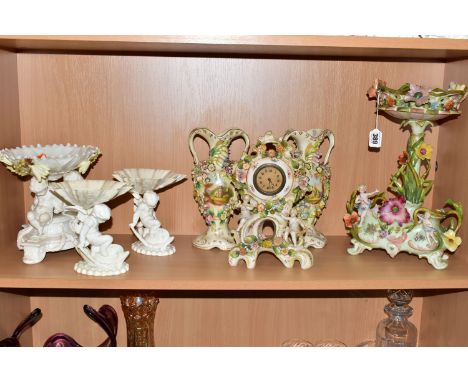SEVEN CERAMIC PIECES WITH MOULDED CHERUB DECORATION, comprising a centrepiece encrusted with flowers and trailing foliage hei
