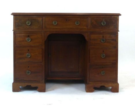 A George III and later mahogany kneehole desk, the surface over an arrangement of nine strung drawers and a single door on br