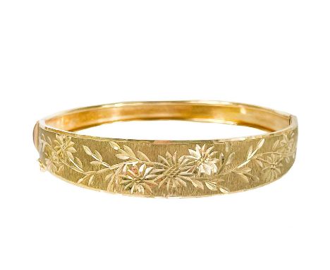 A 9ct gold hinged bangle. The tapered front with floral cut design on a mat textured ground, stamped 375, width 6cm, 9.8g.Lig