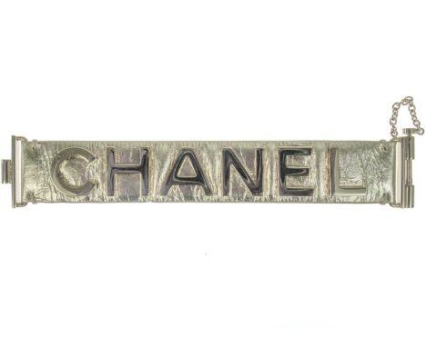 A Chanel light gold tone and gold calfskin leather logo bracelet. In gold lettered CHANEL hardware, slide lock clasp, etched 