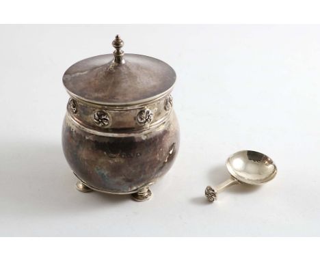 AN EARLY 20TH CENTURY SQUAT CIRCULAR TEA CADDY with a hammered finish, on four circular "seal" feet with a frieze of applied 