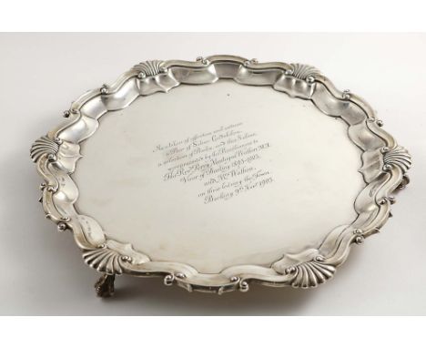 AN EDWARDIAN SALVER of shaped circular outline with a shell and scroll border and ball &amp; claw feet, the centre with an in