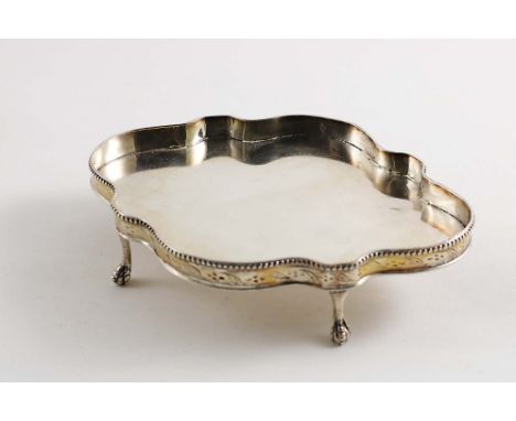 A GEORGE III TEA POT STAND of shaped oval outline on ball &amp; claw feet with a bead border and engraving around the sides, 