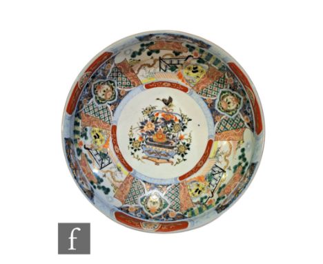 A large Japanese Imari bowl, the central jardinere design decorated with radiating panels of figures and lotus before a diape