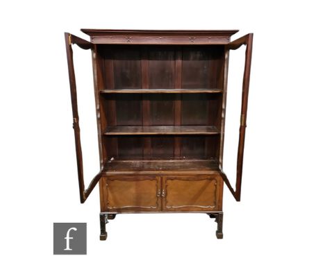 An Edwardian Chippendale style mahogany display cabinet enclosed by a pair of glazed doors below a fluted cornice above a pan