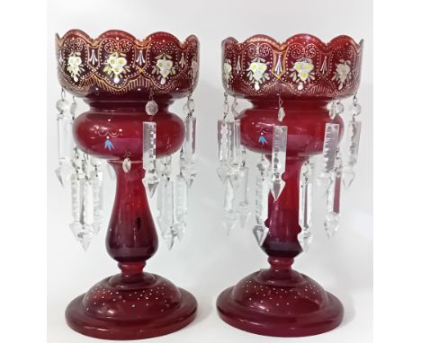 A pair of Victorian ruby glass lustre vases, height 36cm, with glass pendants and gilt painted flowers (one chipped at base).