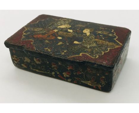 A 19th century Eastern paper mache snuff box featuring two figures in a cartouche.