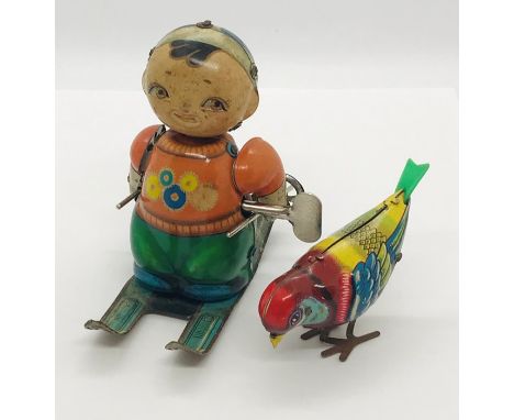 A vintage tinplate clockwork skier and pecking tinplate bird with keys (key for bird in office)