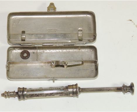 A Down Bros syringe in fitted white metal case, the glass phial with engraved scale and with white metal tip and plunger, all